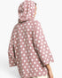 A person shown from the back wearing a dusty pink hooded sweatshirt with a white polka dot pattern, photographed against a light gray studio background.