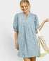Woman wearing a light blue dress holding a beige bag on a white background
