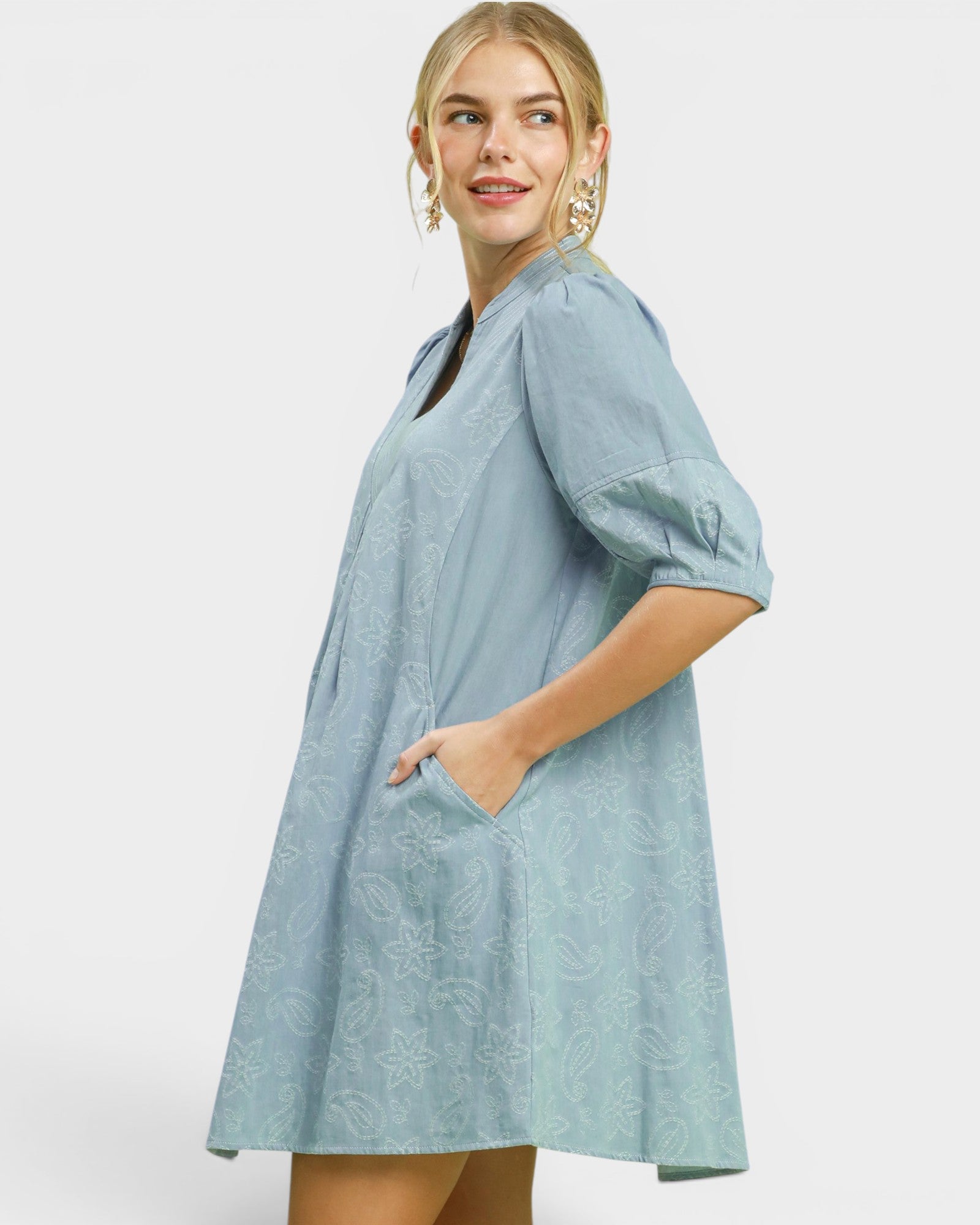 Woman wearing a light blue dress with a plain background