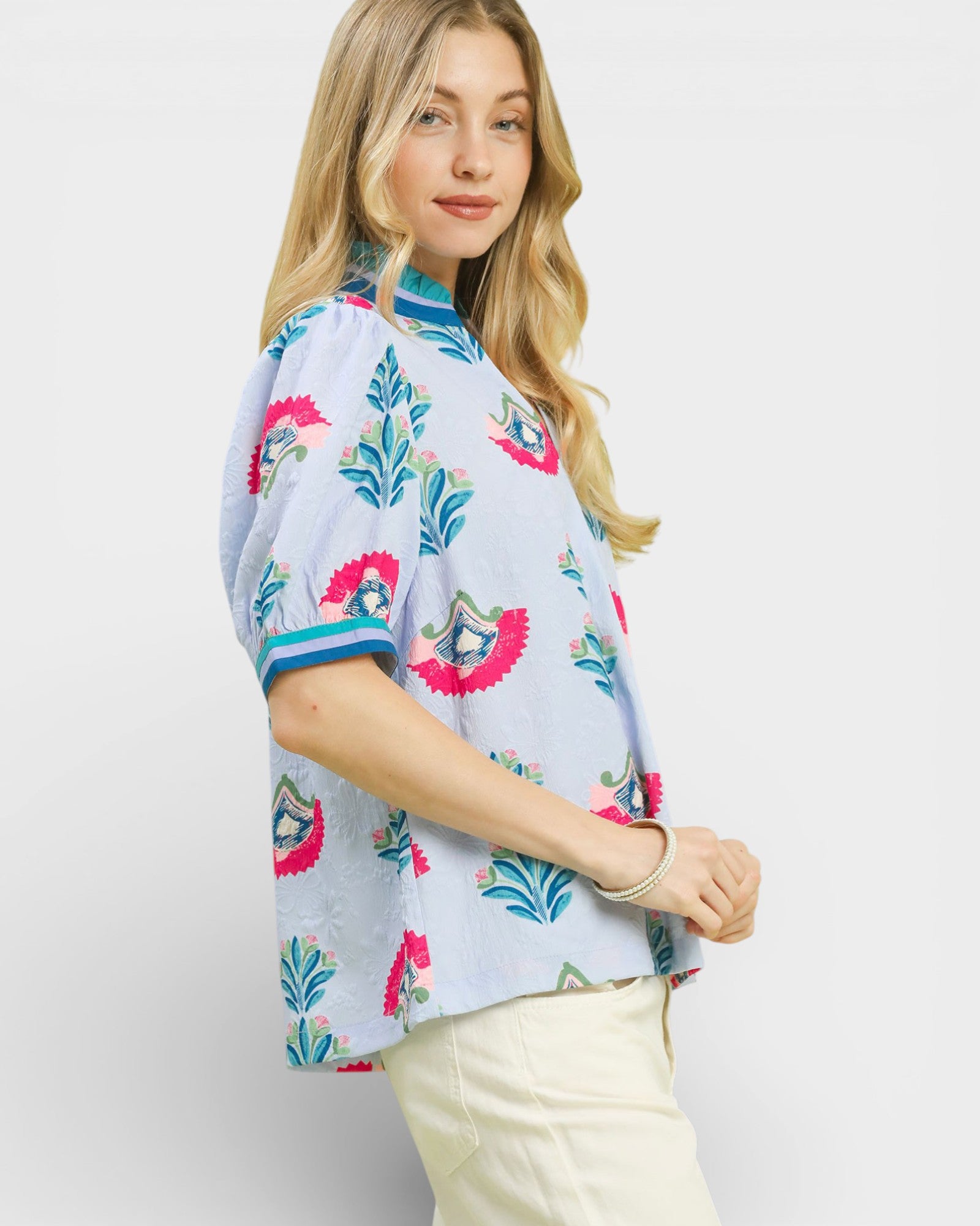 Woman wearing a colorful floral blouse with a plain background