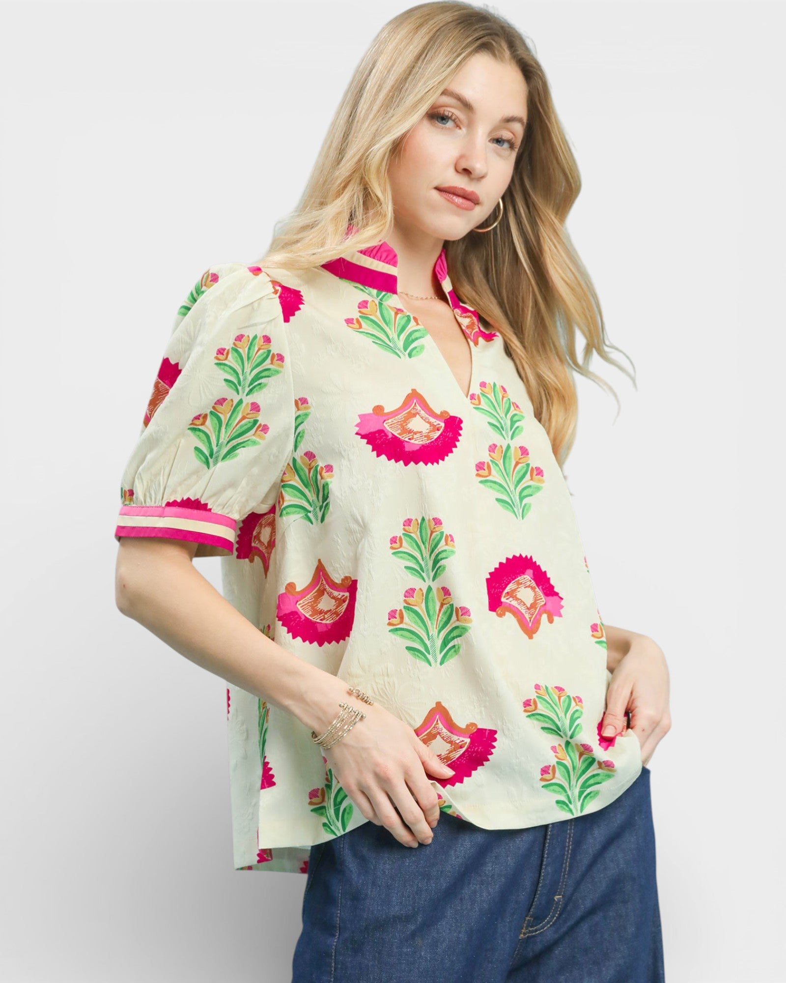 Woman wearing a floral blouse with pink and green patterns on a white background