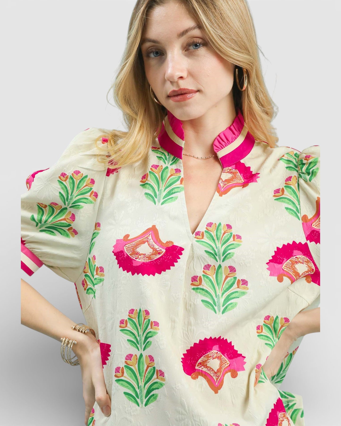 Woman wearing a cream-colored blouse with pink and green floral patterns on a white background