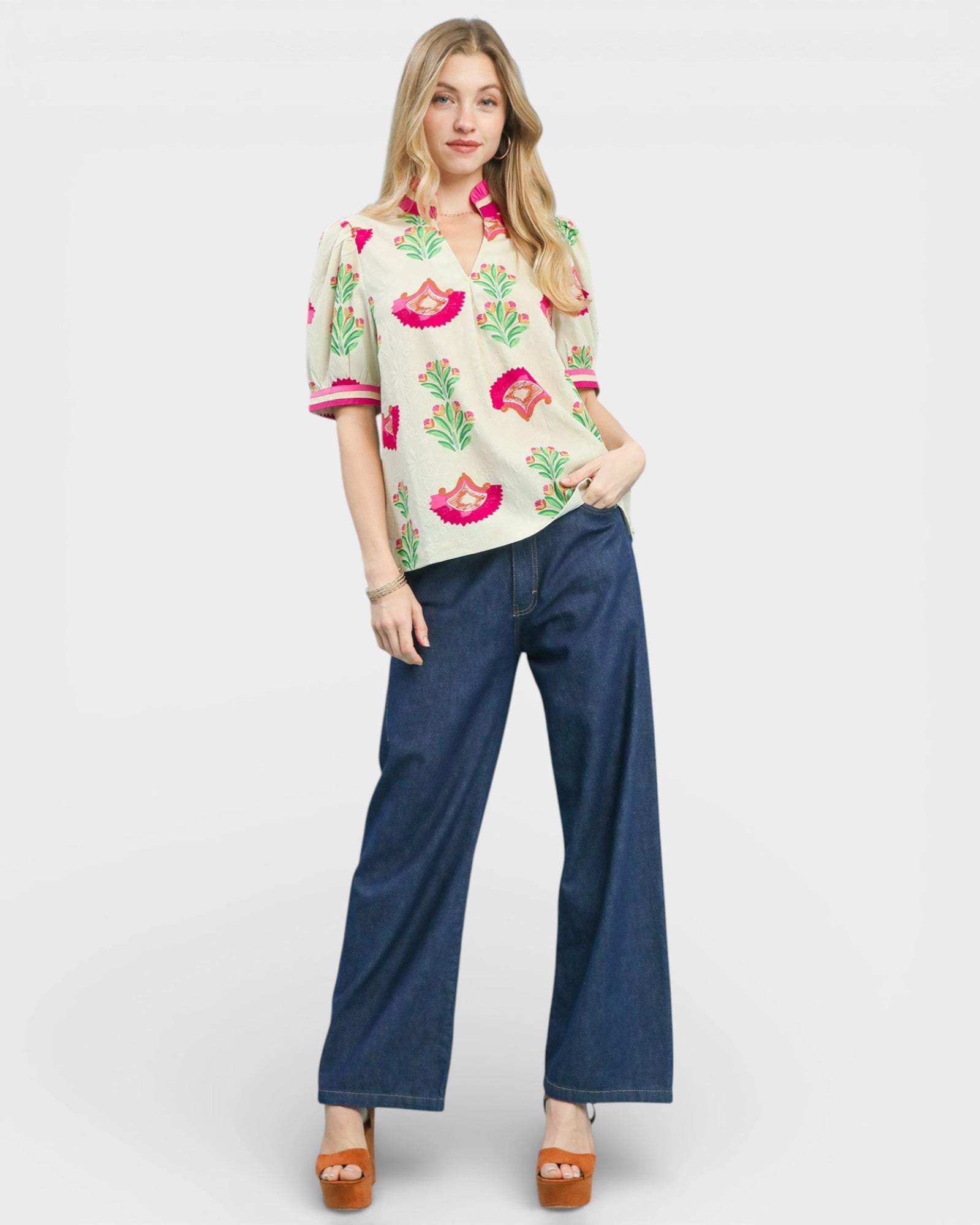 Woman wearing a floral blouse and blue pants on a white background