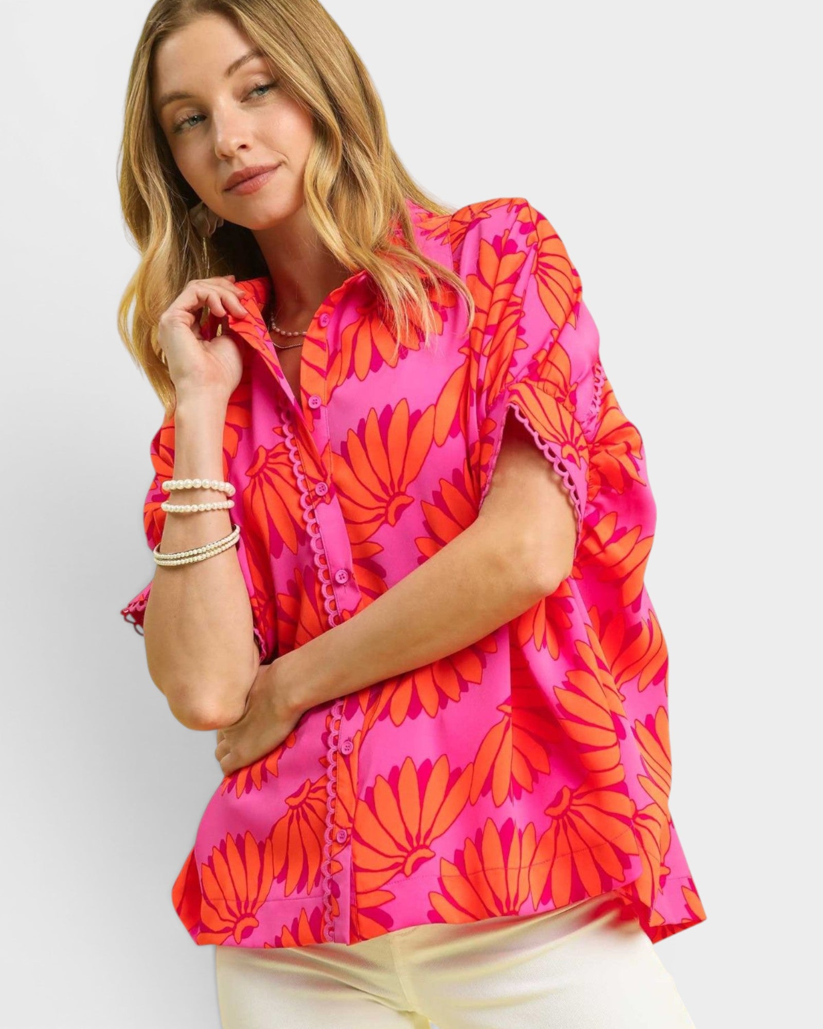 Woman wearing a bright pink and orange patterned top on a white background