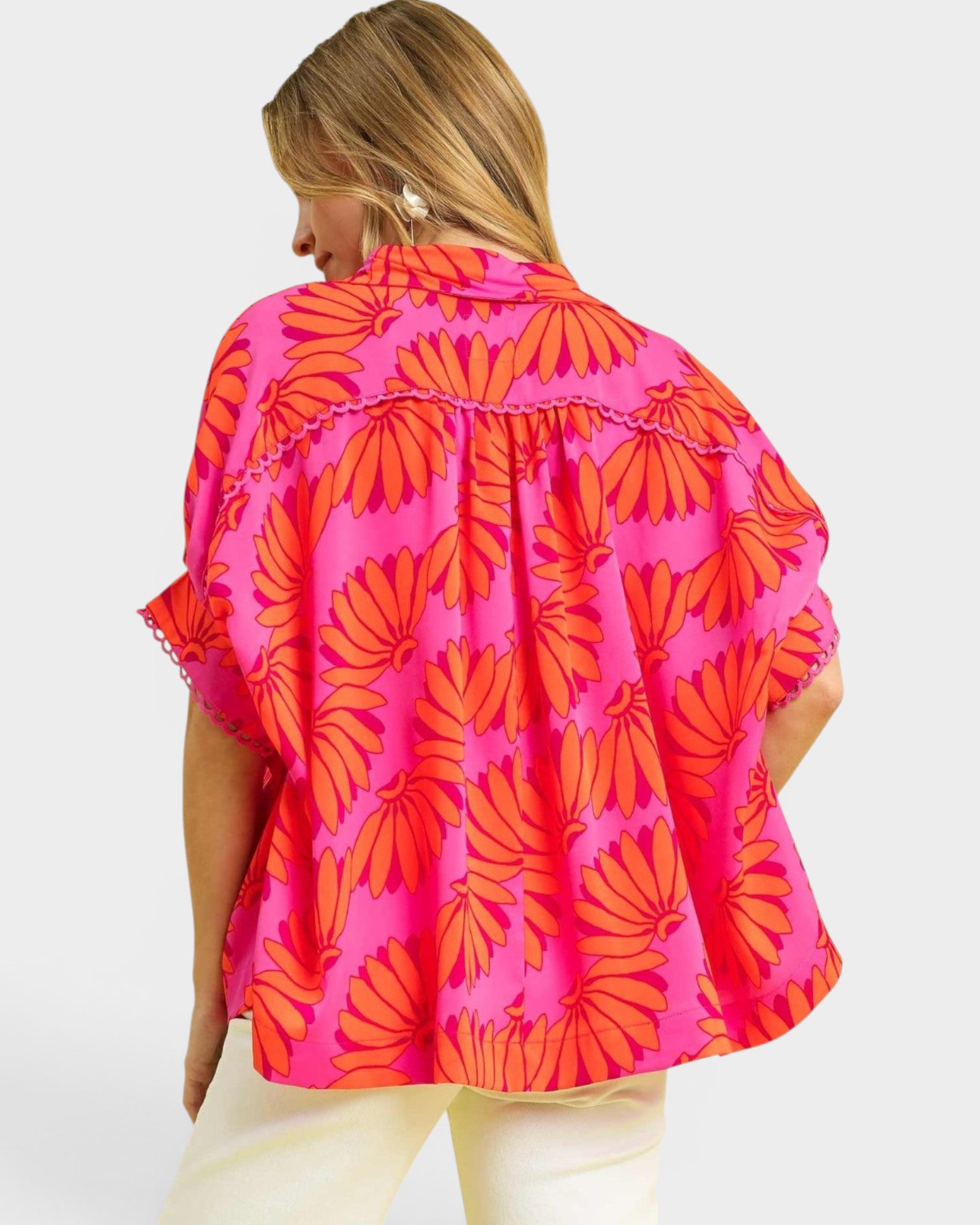 Person wearing a bright pink and orange floral patterned shirt on a white background