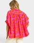 Person wearing a bright pink and orange floral patterned shirt on a white background