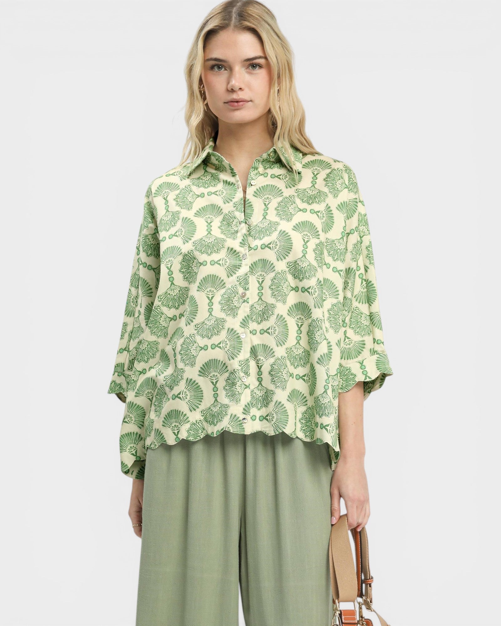 Woman wearing a green patterned shirt and green pants on a white background