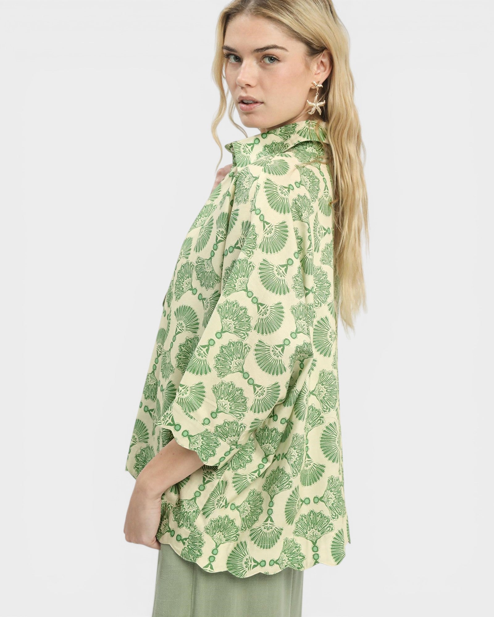 Woman wearing a green and white patterned blouse on a white background