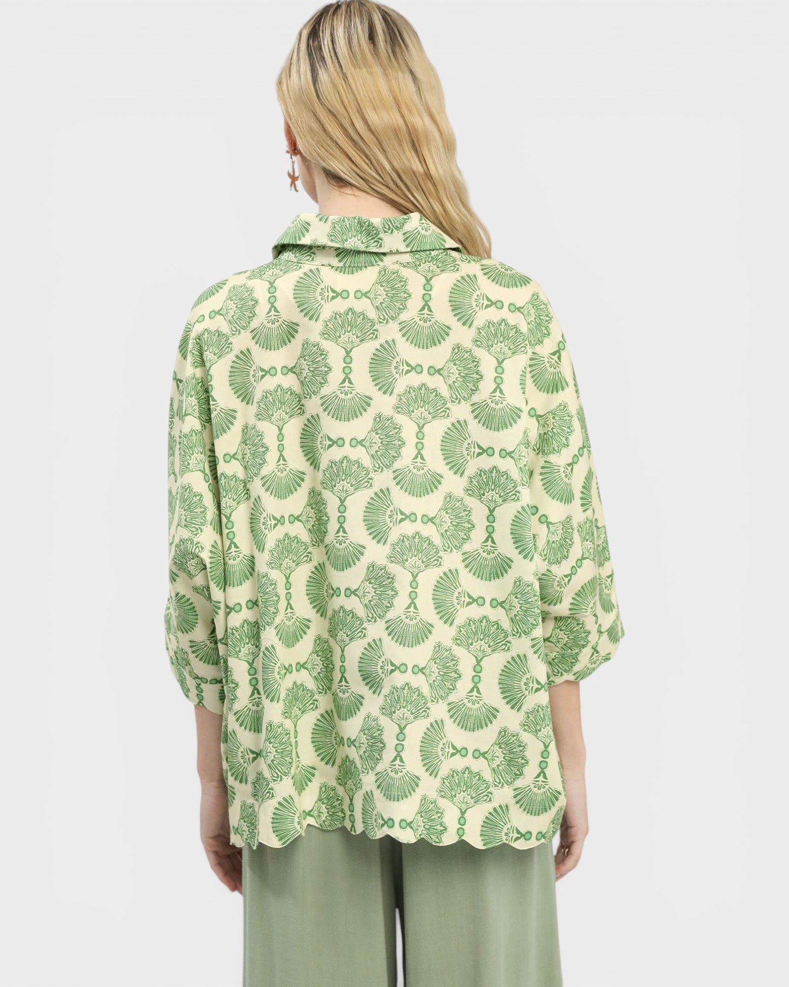 Person wearing a green and white patterned shirt on a light gray background