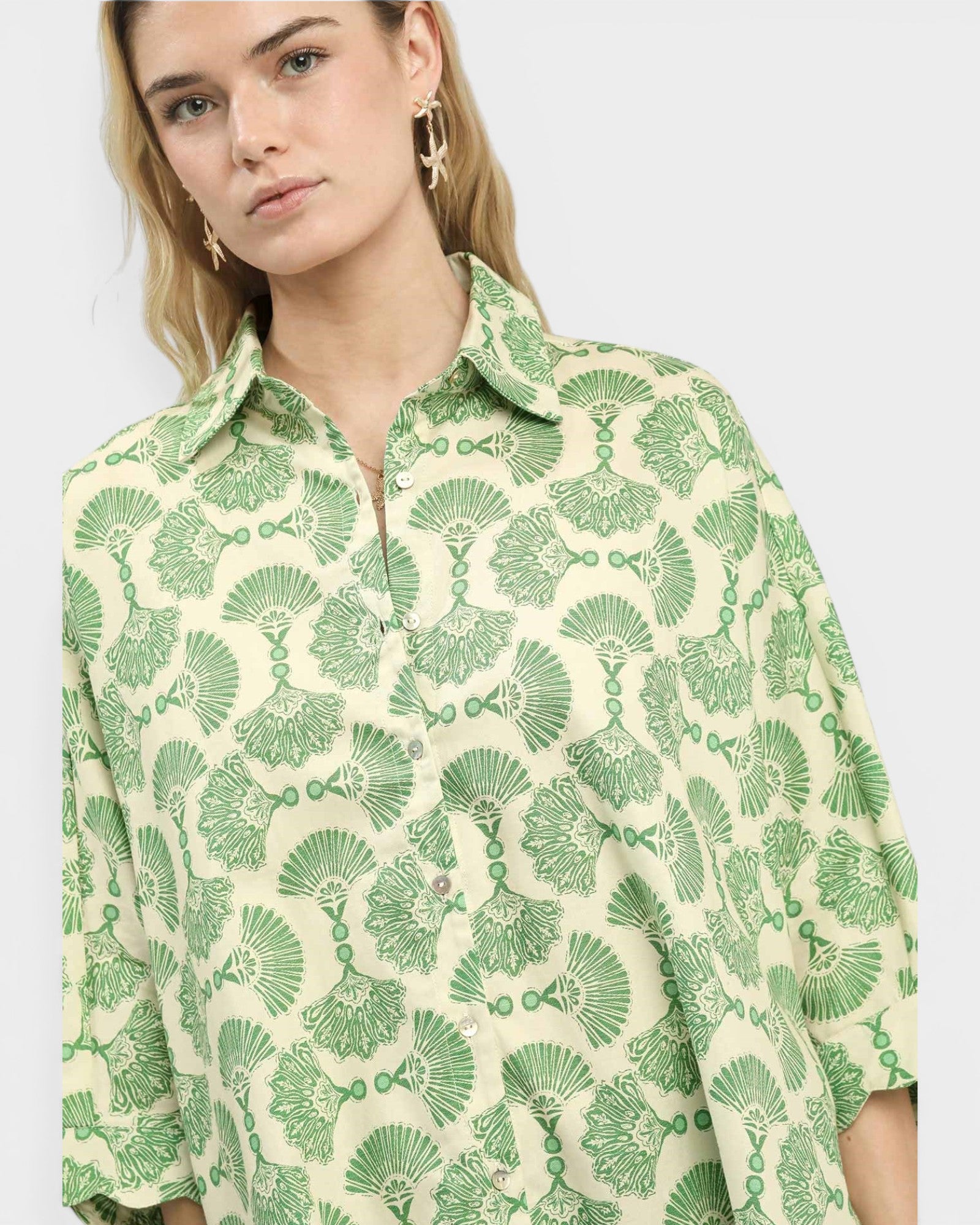 Woman wearing a green and white patterned shirt on a plain background