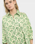 Woman wearing a green and white patterned shirt on a plain background
