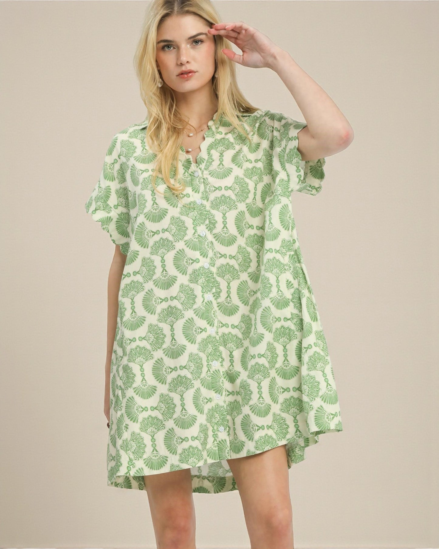 Woman wearing a green and white patterned dress against a beige background