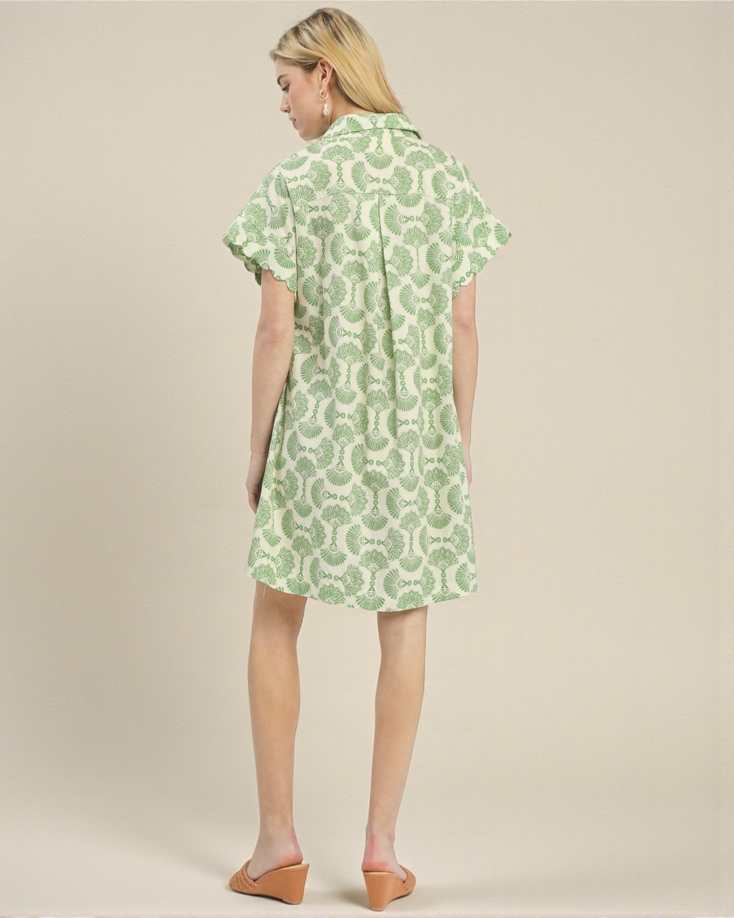 Woman wearing a green patterned dress on a beige background