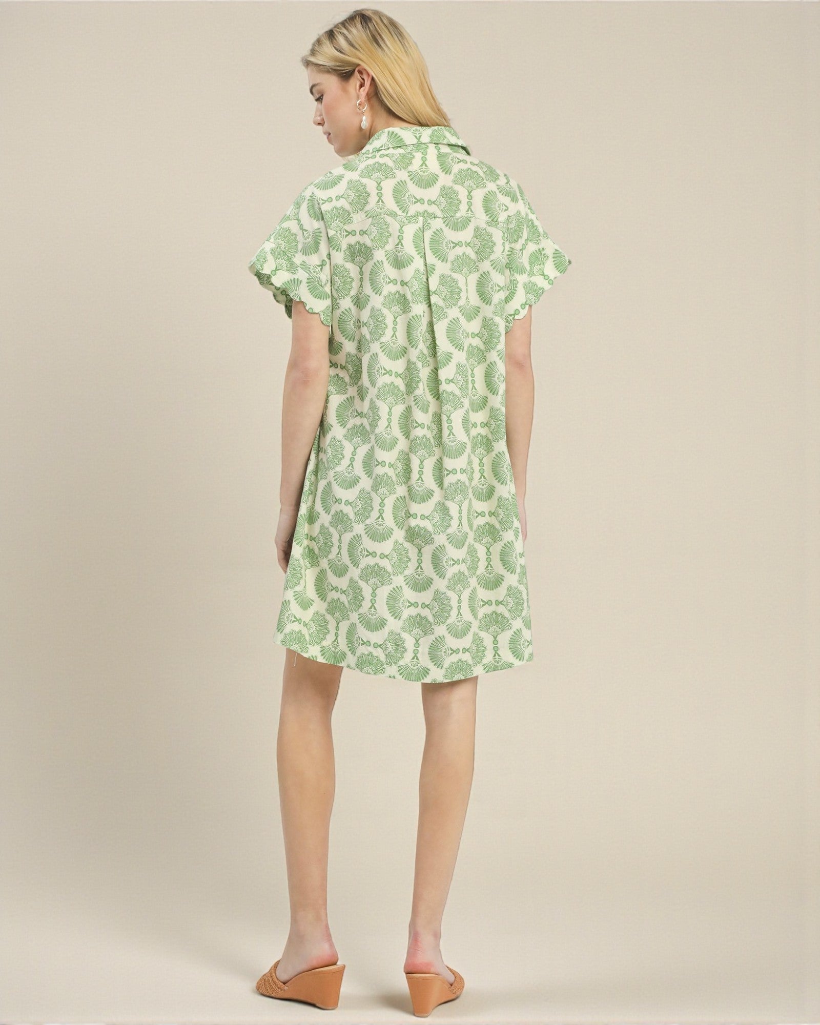 Woman wearing a green patterned dress on a beige background