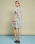 Woman wearing a patterned dress against a beige background