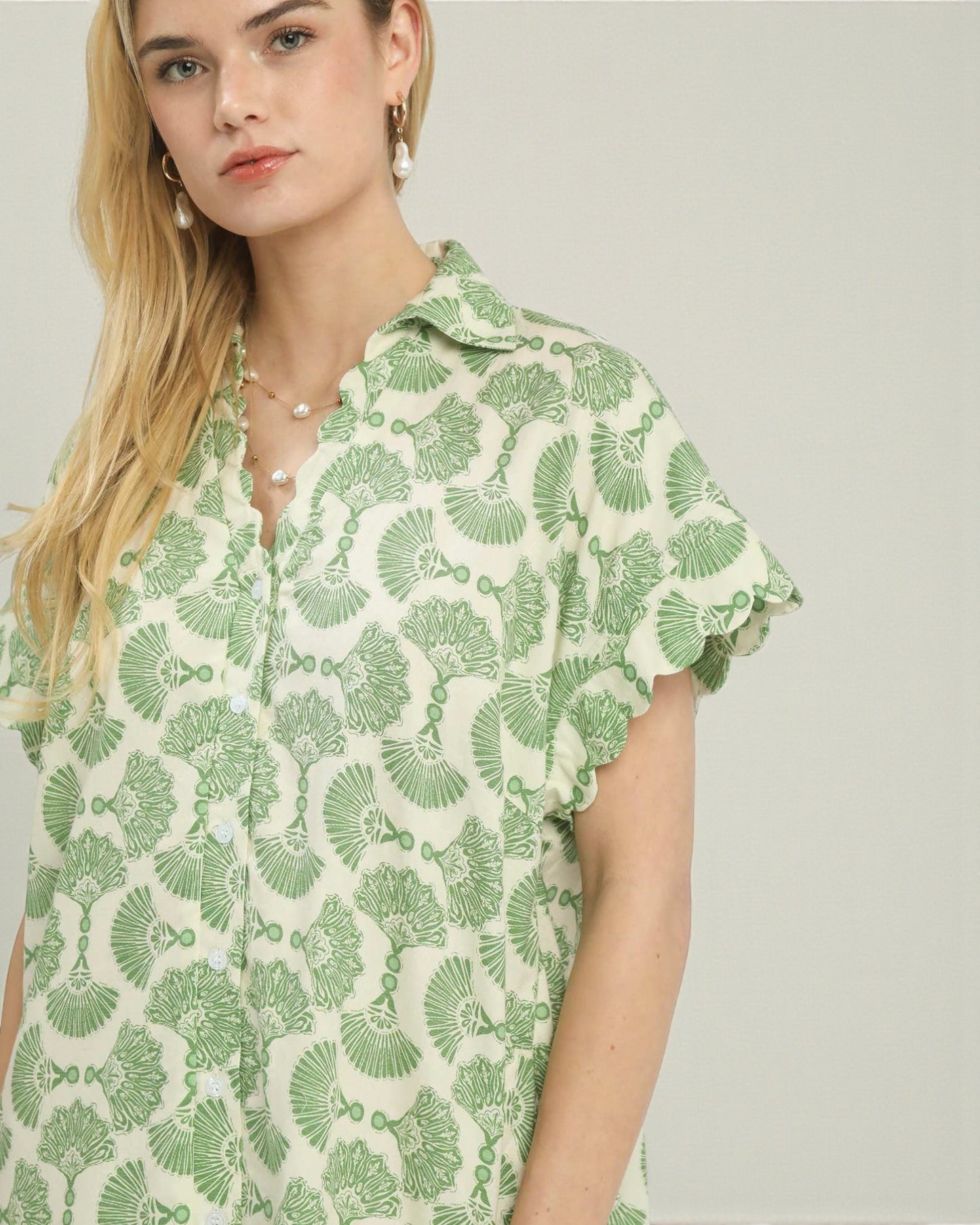 Woman wearing a green and white patterned shirt against a plain background