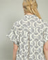 Person wearing a patterned shirt with a neutral background