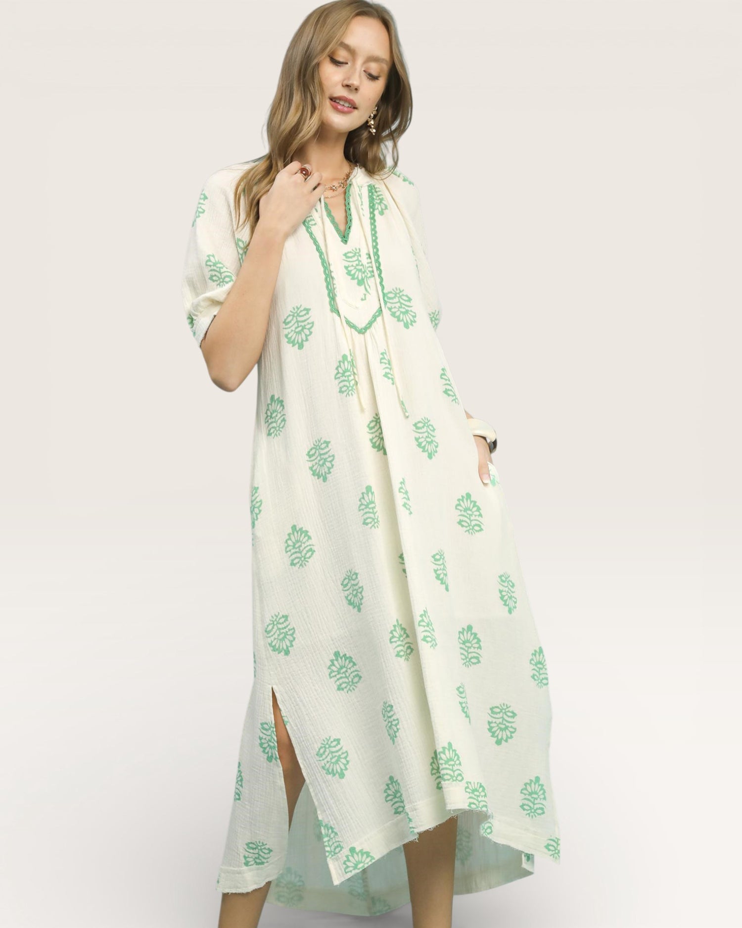 Woman wearing a white dress with green floral patterns on a white background