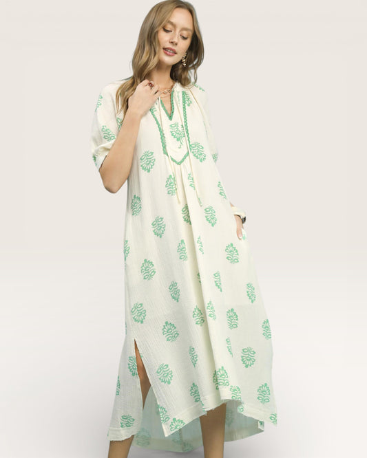 Woman wearing a white dress with green floral patterns on a white background