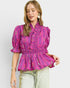 Woman wearing a pink patterned blouse against a light background