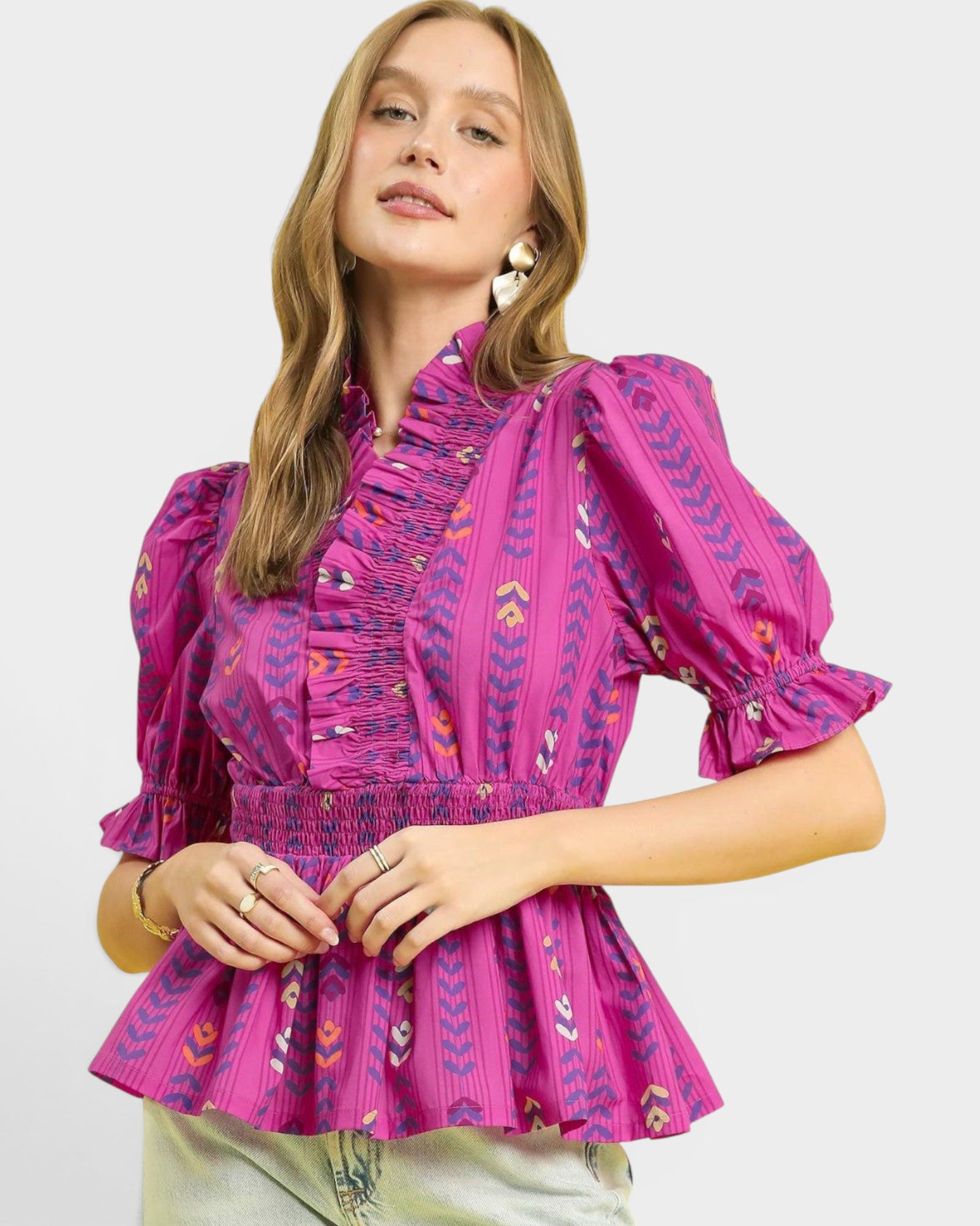 Woman wearing a pink patterned blouse on a plain background