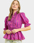 Woman wearing a pink patterned blouse on a plain background