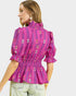 Woman wearing a pink patterned blouse on a light gray background