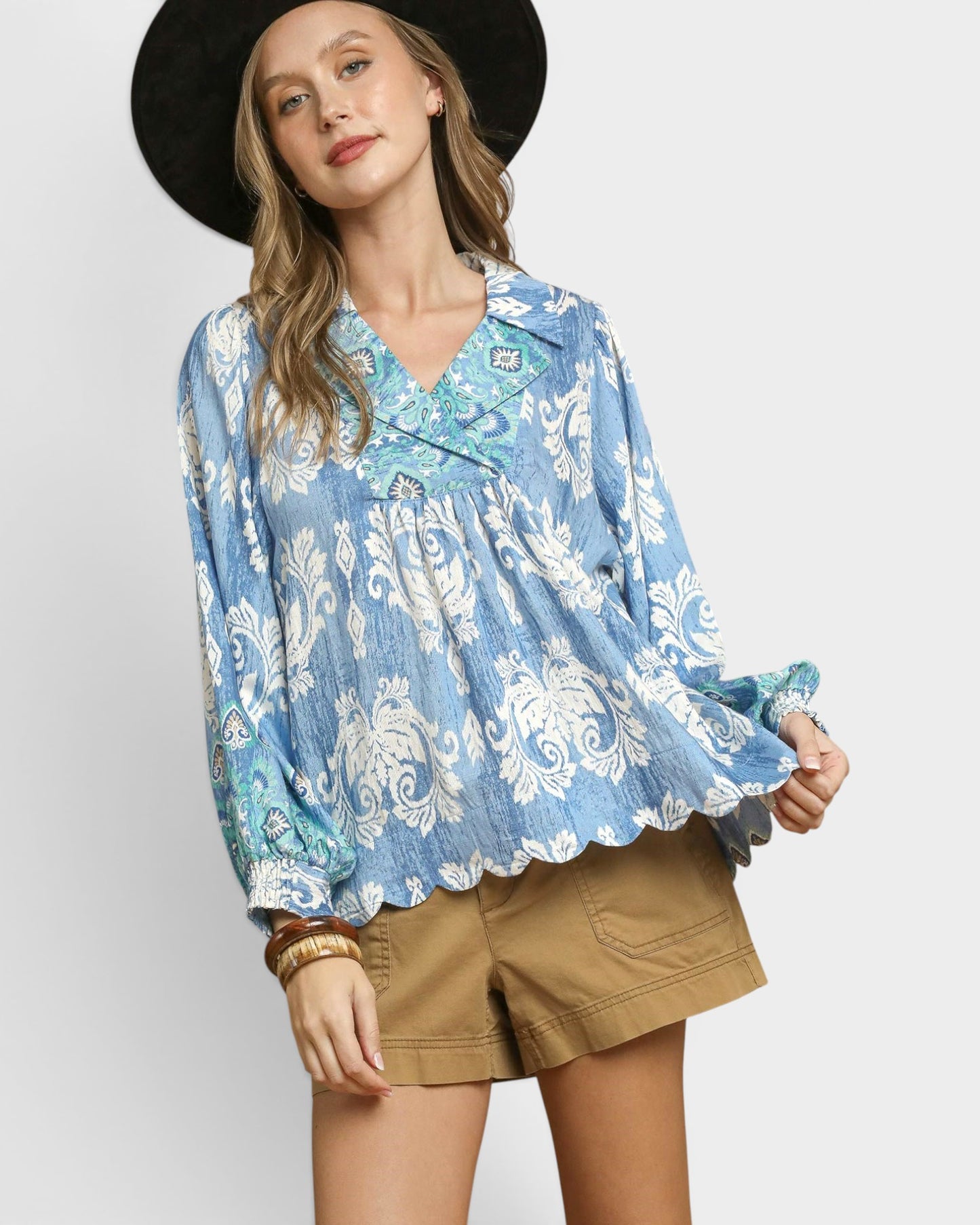 Woman wearing a blue floral blouse and brown shorts on a white background