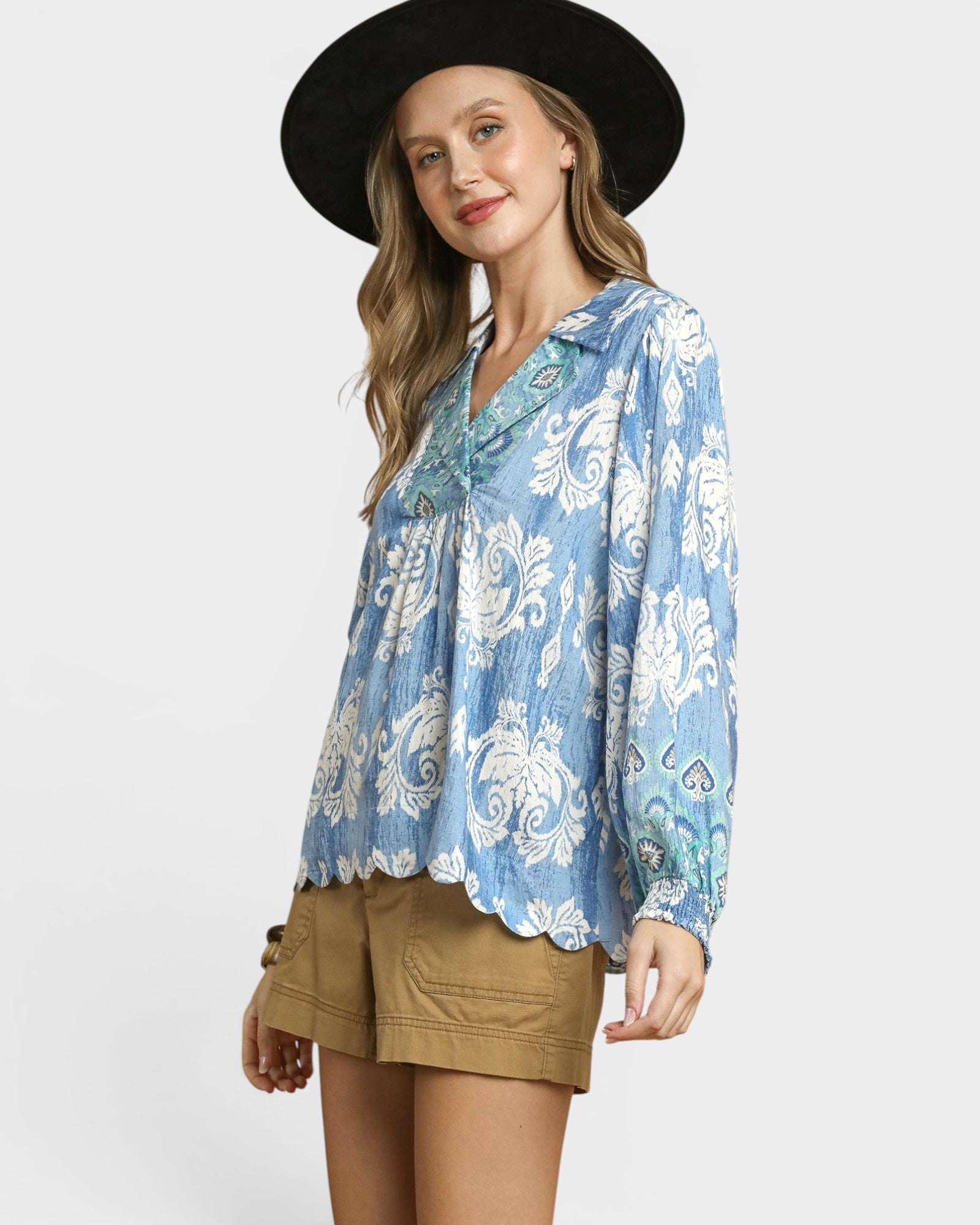 Woman wearing a blue floral blouse and black hat on a white background