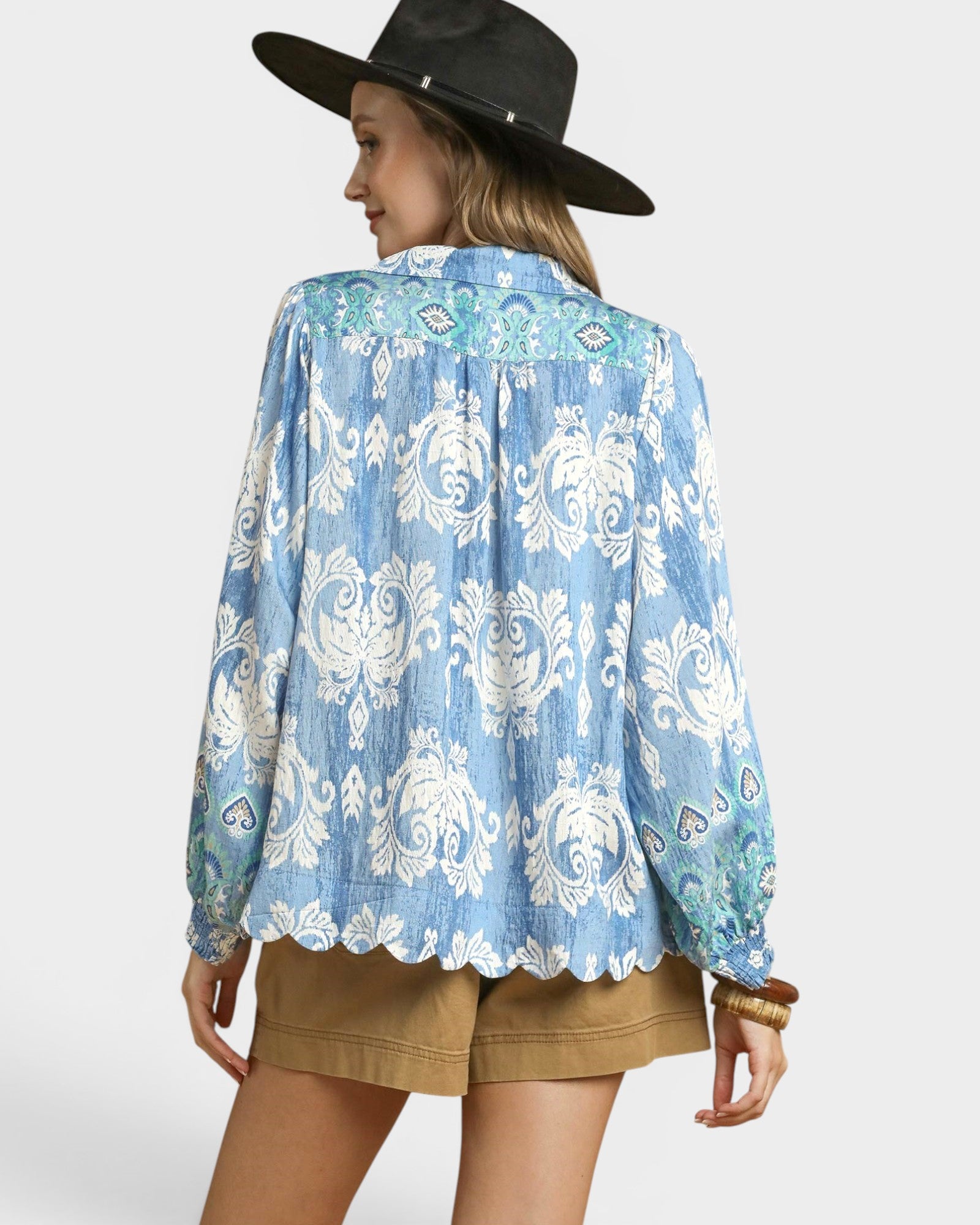 Woman wearing a blue patterned shirt and black hat on a white background