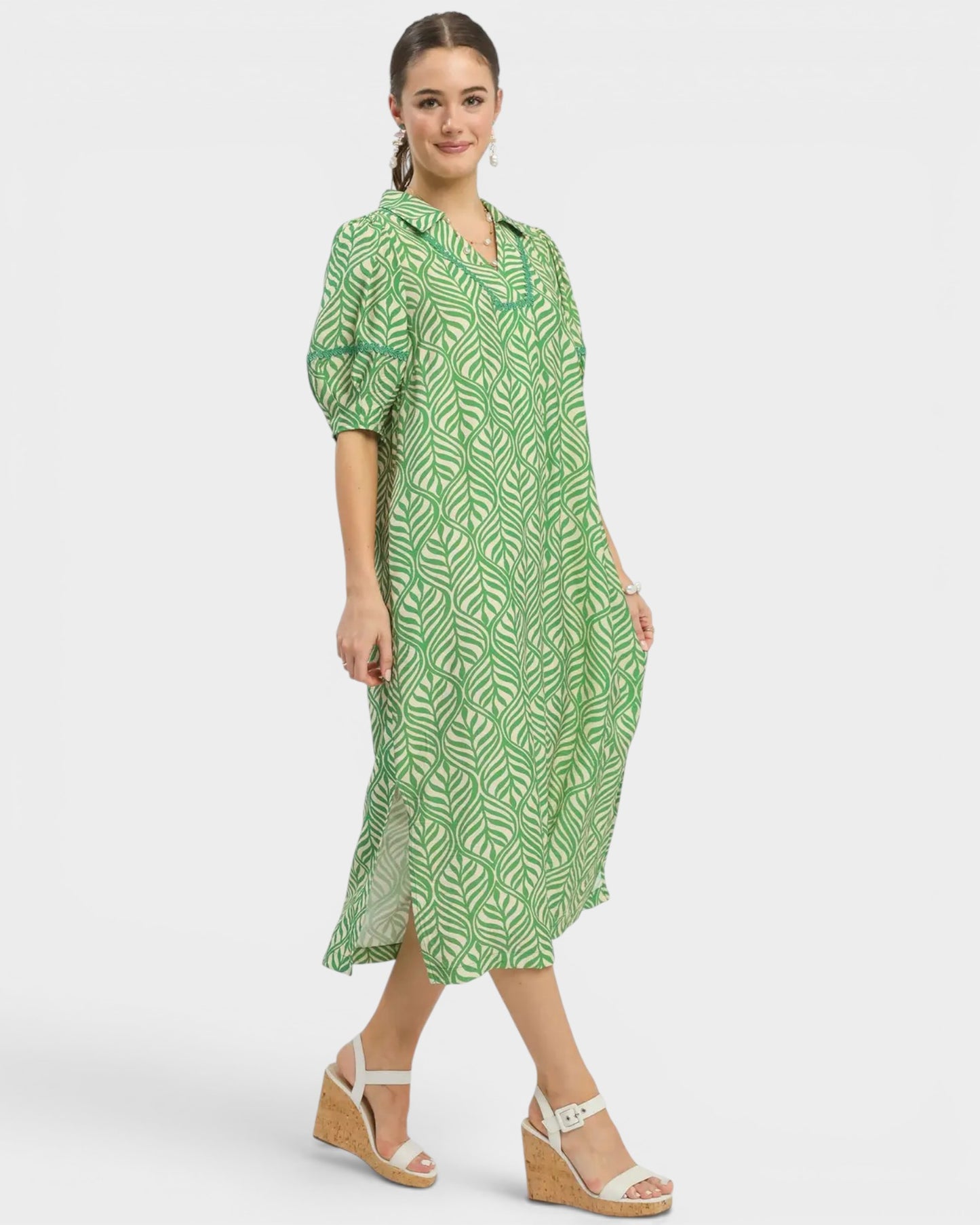 Woman wearing a green patterned dress on a white background