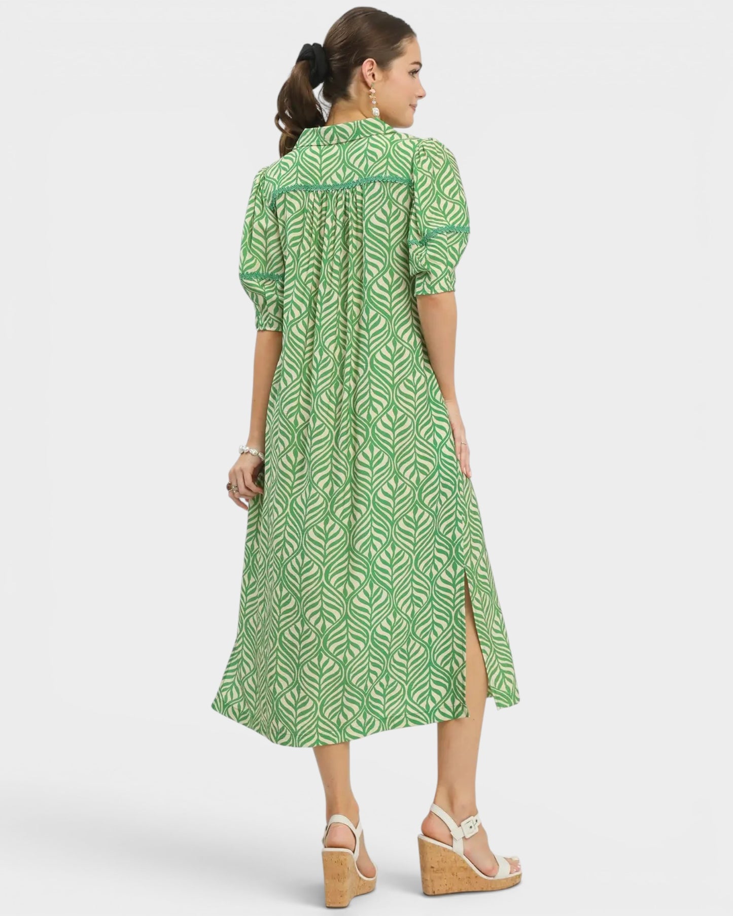 Woman wearing a green patterned dress on a white background