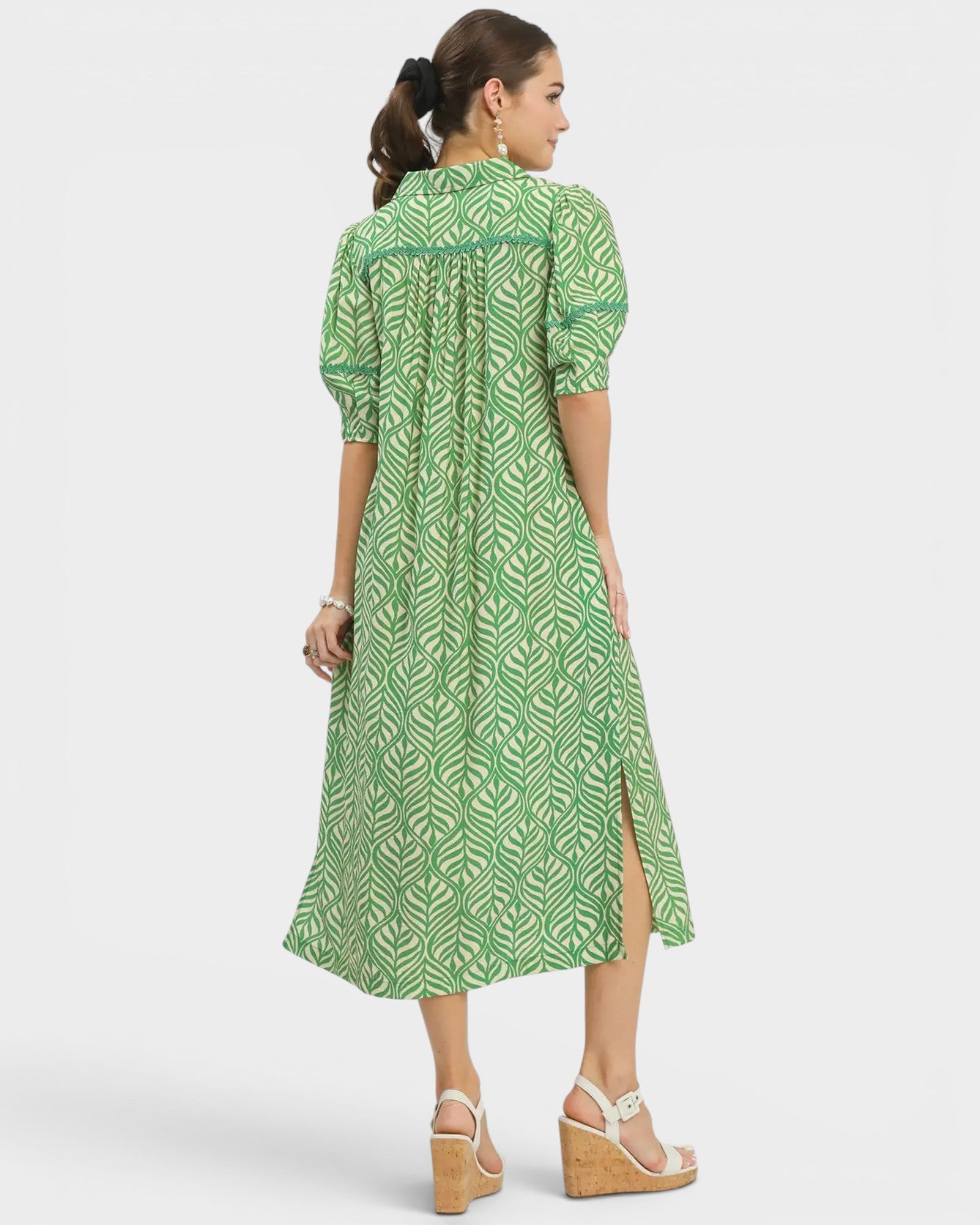 Woman wearing a green patterned dress on a white background