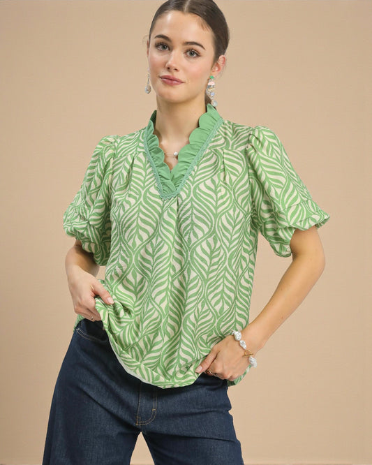 Woman wearing a green patterned blouse against a beige background