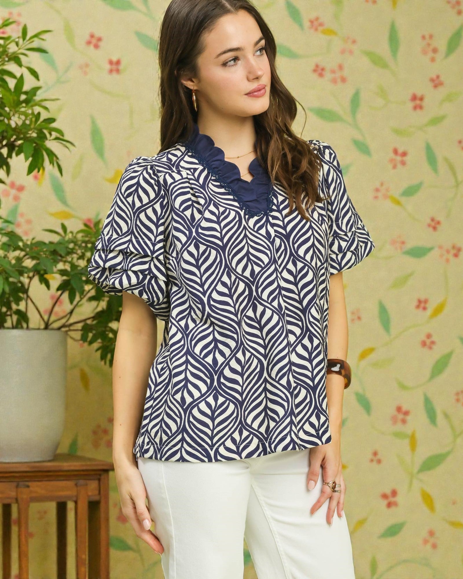 Woman wearing a blue and white patterned blouse with a floral background