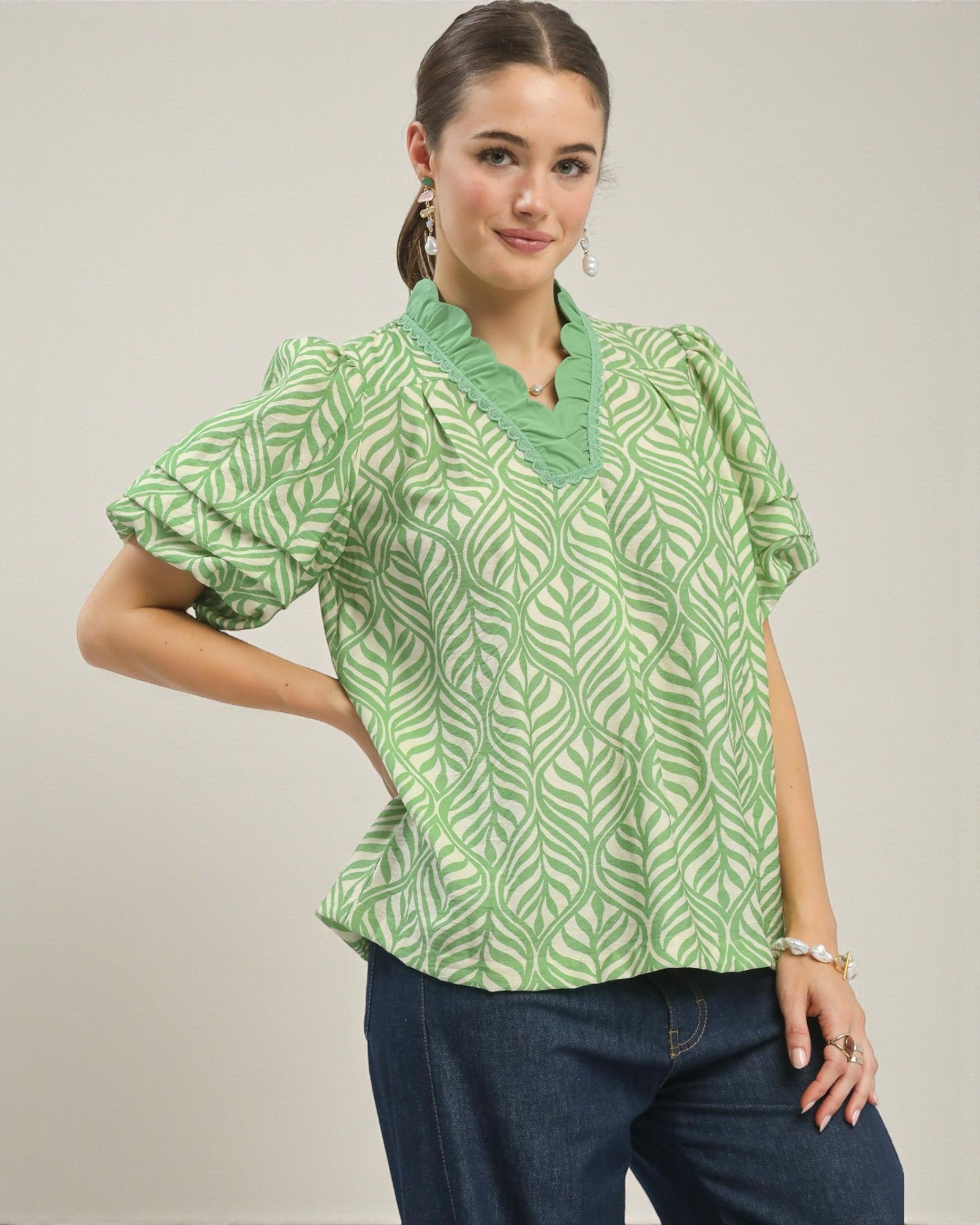 Woman wearing a green patterned blouse with a plain background