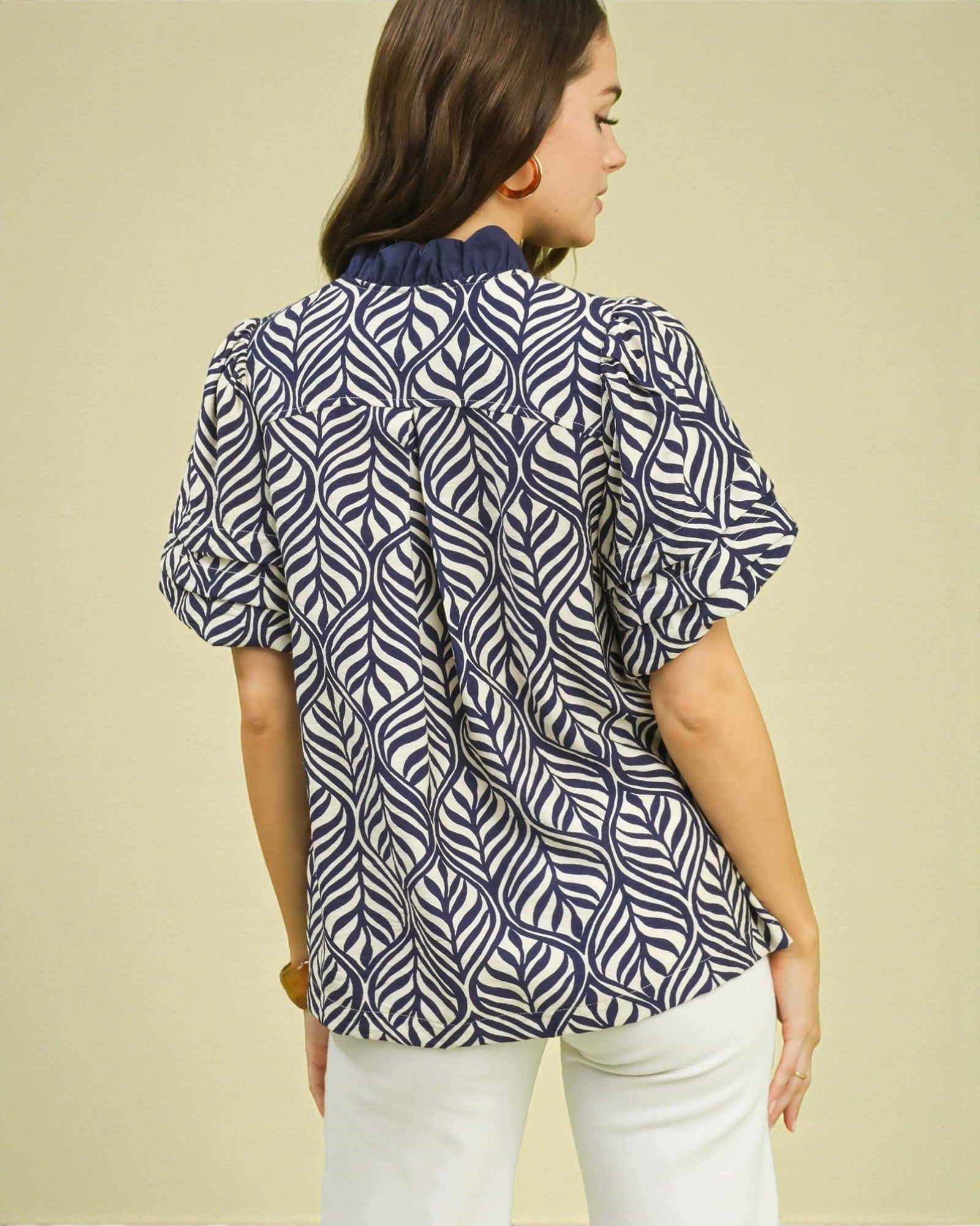 Woman wearing a blue and white patterned blouse against a beige background