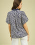 Woman wearing a blue and white patterned blouse against a beige background