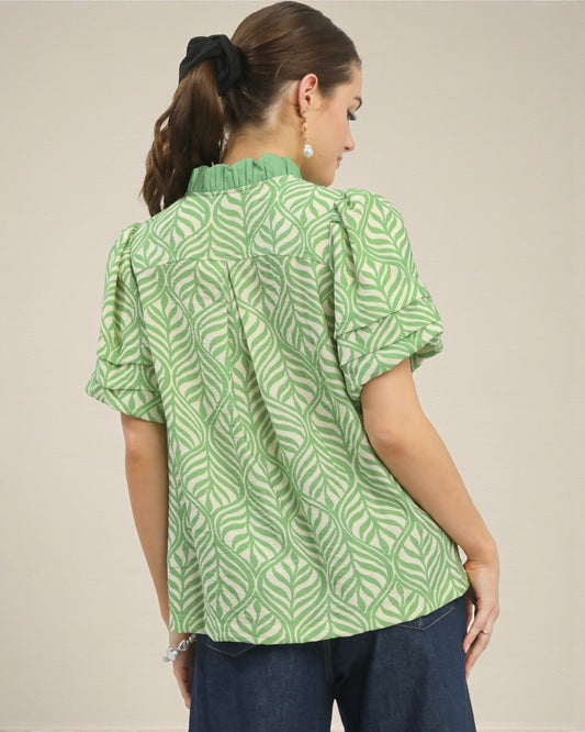 Woman wearing a green patterned blouse against a neutral background