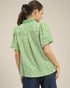 Woman wearing a green patterned blouse against a neutral background