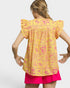 Woman wearing a yellow and pink patterned top with ruffled sleeves on a white background