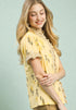 Woman wearing a yellow embroidered blouse against a light blue background