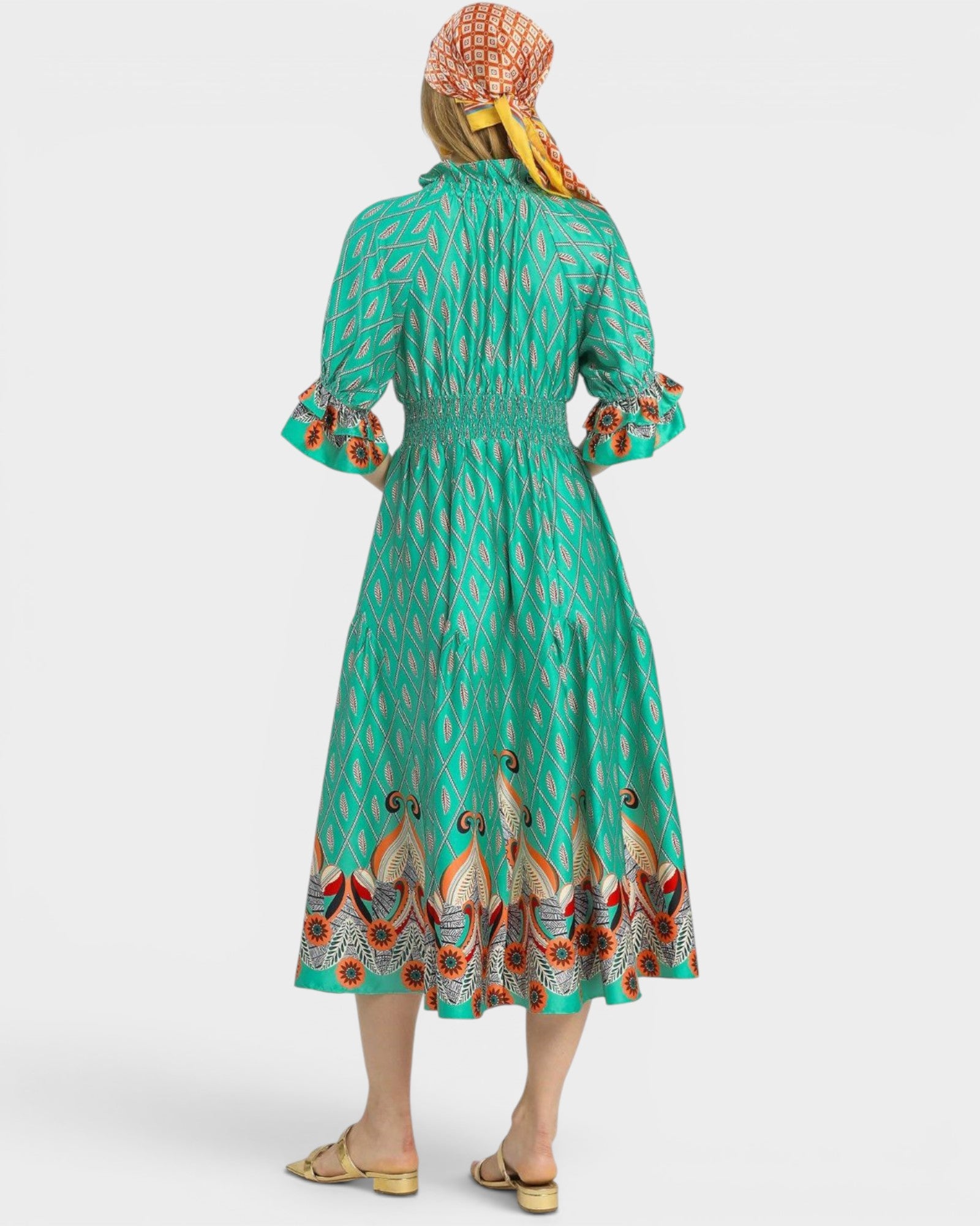 Woman wearing a green dress with bird pattern and a headscarf on a white background