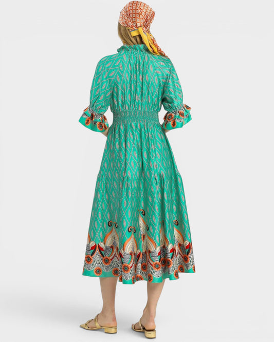 Woman wearing a green dress with bird pattern and a headscarf on a white background
