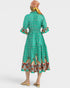 Woman wearing a green dress with bird pattern and a headscarf on a white background