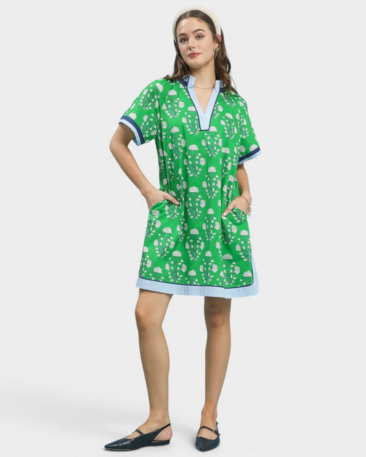 Woman wearing a green dress with white floral pattern on a white background