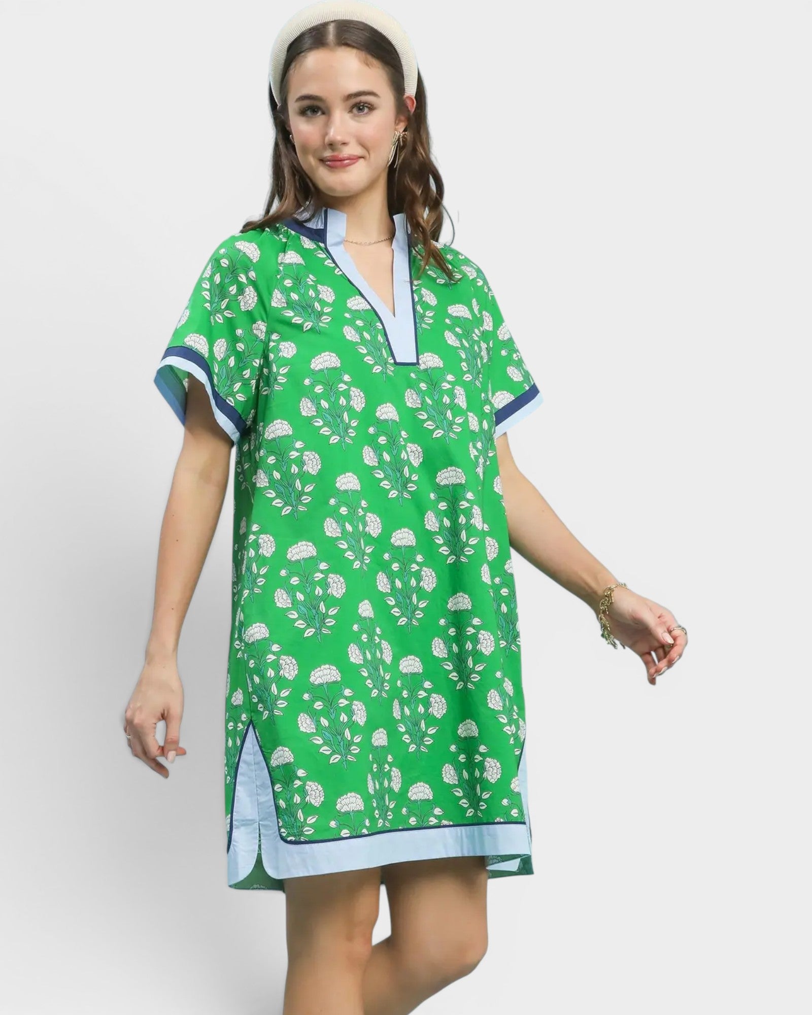 Woman wearing a green patterned dress with blue accents on a white background