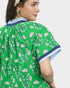 Woman wearing a green dress with white floral pattern on a plain background