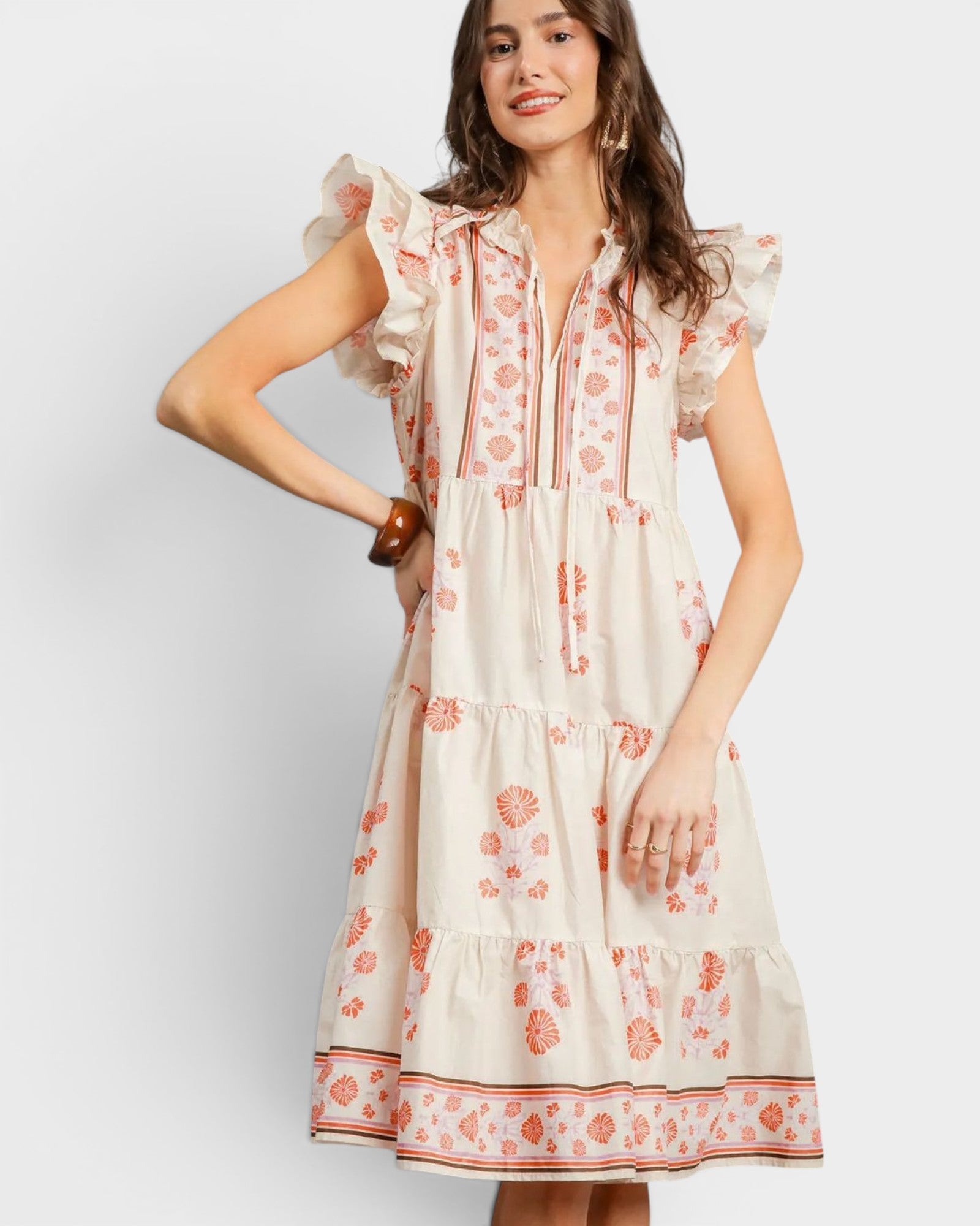 Woman wearing a white dress with orange floral pattern on a plain background