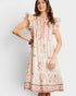 Woman wearing a white dress with orange floral pattern on a plain background